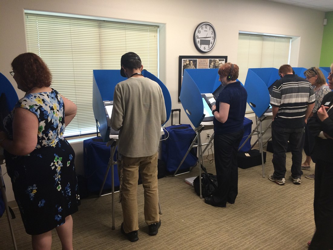 Five people standing each using individual voting equipment.