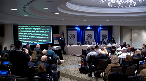 Doug Chapin standing and speaking while 5 workshop participants are seated while audience looks on