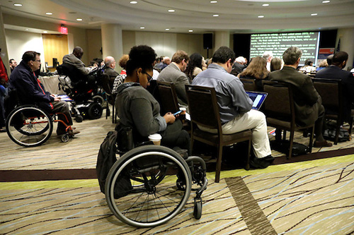 Attendees at the forum some in wheelchairs listening to the workshop participants